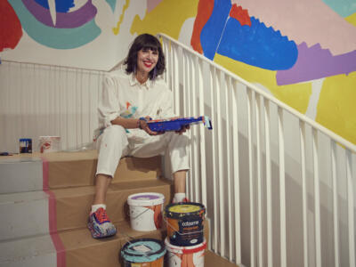Kvinna sitter i trappa med målarfärger runt sig