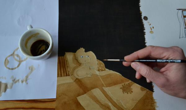 En kopp espresso och en illustration färglagd med kaffe. En hand håller i en pensel ovanför illustrationen. 