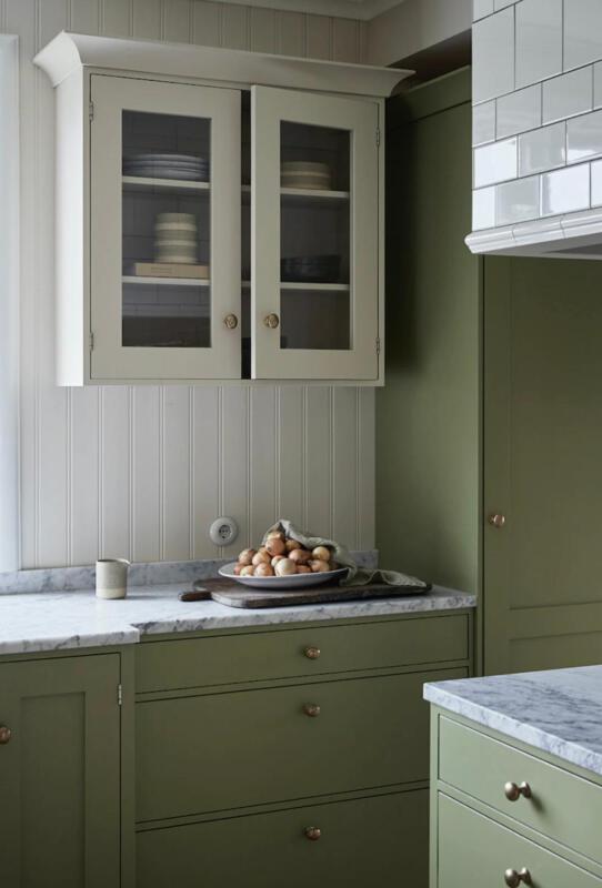 Grönt kök med marmorbänk där det står ett fat med gul lök på