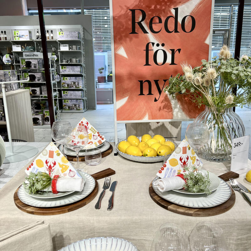 En bild som föreställer ett dukat bord i en Åhlénsbutik. På bilden syns kräfthattar.