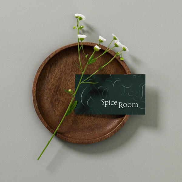 Business card for an elegant Indian restaurant placed on a wooden plate with flowers