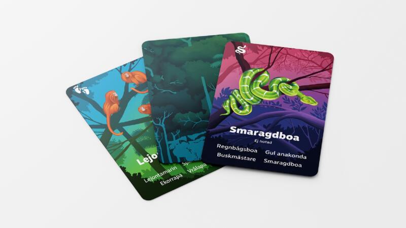 Tre kort ur spelet Finns i Amazonas, en med en bild på aport, en där man ser kortens baksida och en med en bild på en grön orm.