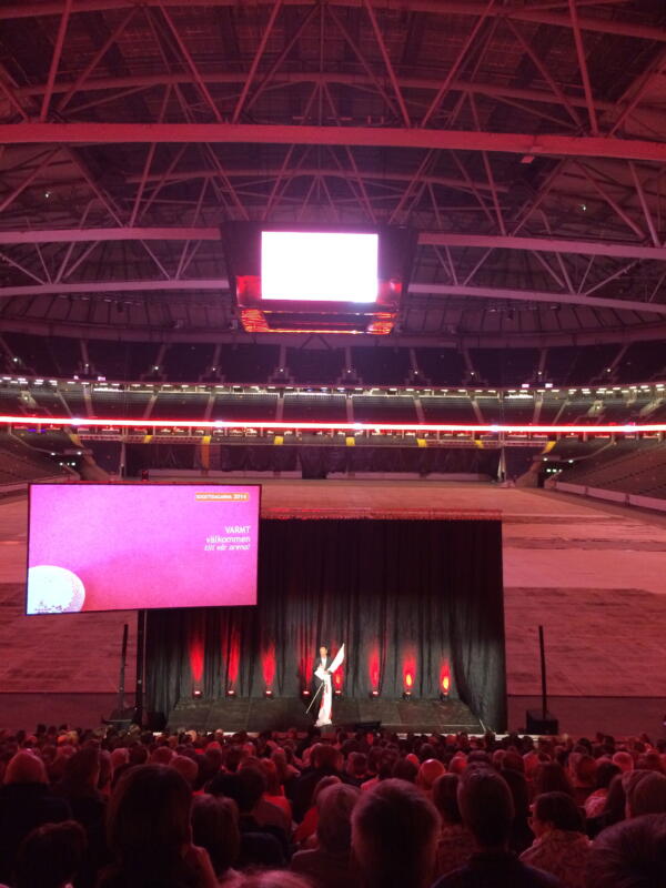 Bild av profilerat event på Friends Arena, vi ser storbildsskärm med design, publikhavet och vd på Scen.