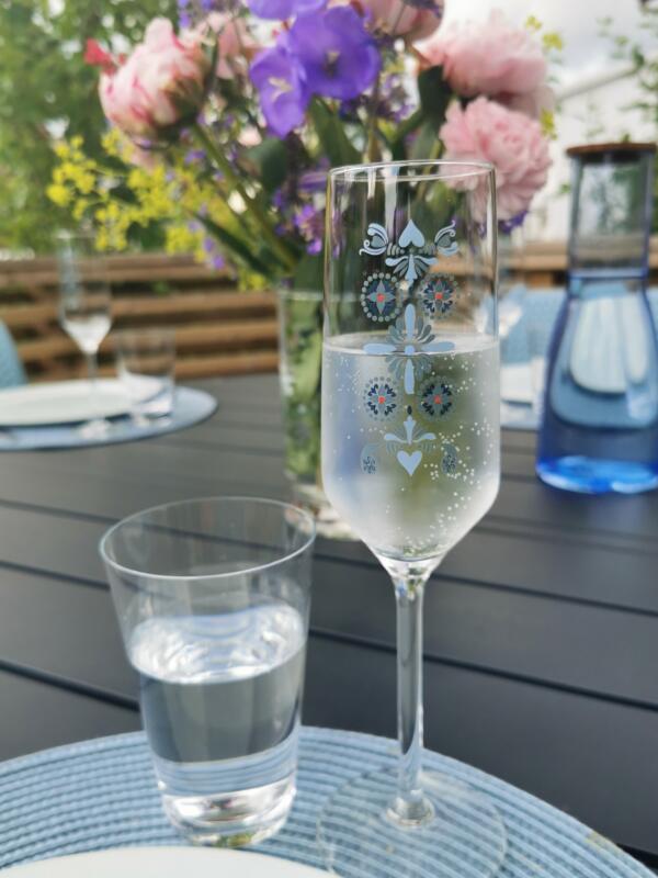 Champagne glass with printed designs #mitthälsingland, flowers in the back. From midsummer fiest in Sweden. Design Maria Helgars.