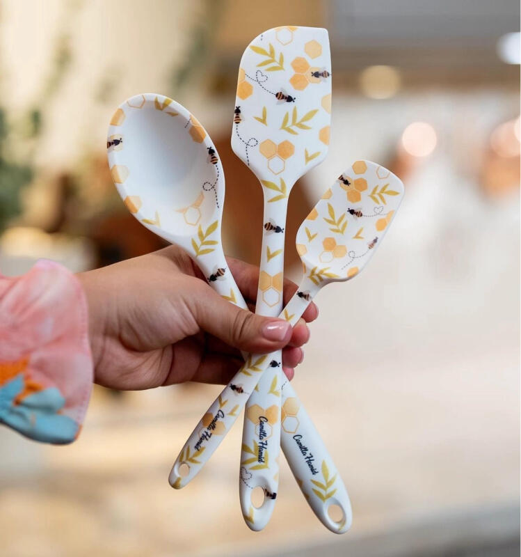 Hand holding baking tools with bespoke bee pattern created for Camilla Hamid