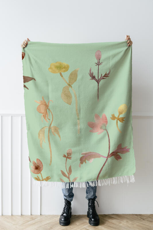 en person som håller upp en ljusgrön filt med blommor på