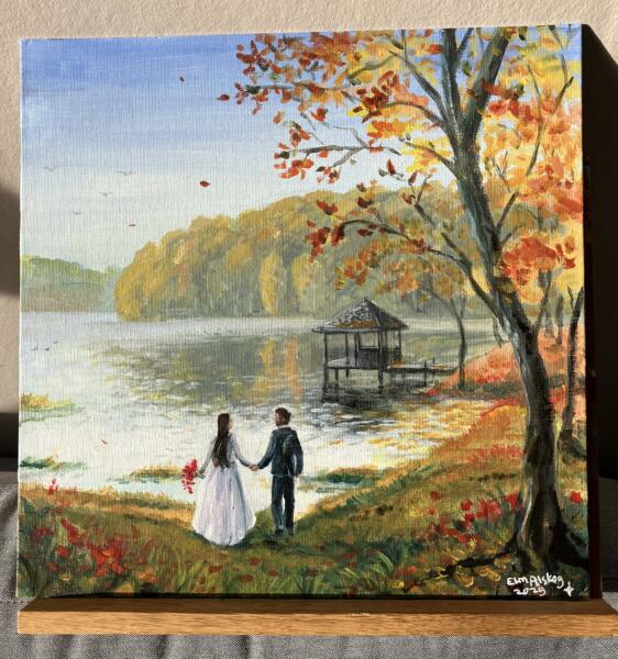 Ett brudpar står vid en sjöstrand, det är höst och orange och röda löv. I bakgrunden syns en brygga med ett lusthus och skogen bortom sjön. Akrylmålning. 