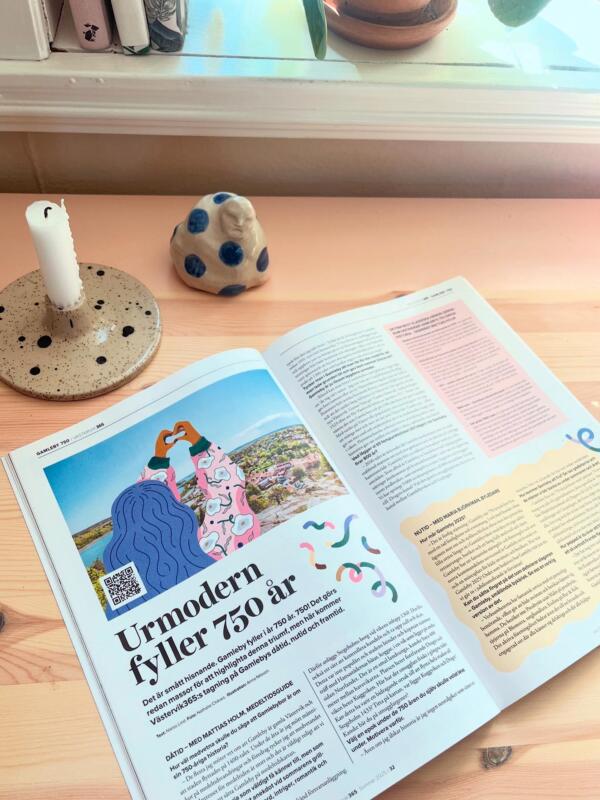 Flicka/tjej/kvinna som sträcker upp händerna och gör en hjärtan-symbol med händerna. Hon har blått hår, blommig jacka och är omgiven av girlanger. 