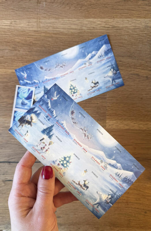 Illustration och grafisk design till PostNords julfrimärken 2024 "En sagolik jul", akvarell. Frimärken till jul, motiv av ett magiskt vinterlandskap med djur som isbjörn och älg, snö, skog, tomtens släde, en julgran och luciatåg. Magisk vinter med natthimmel och stor måne.