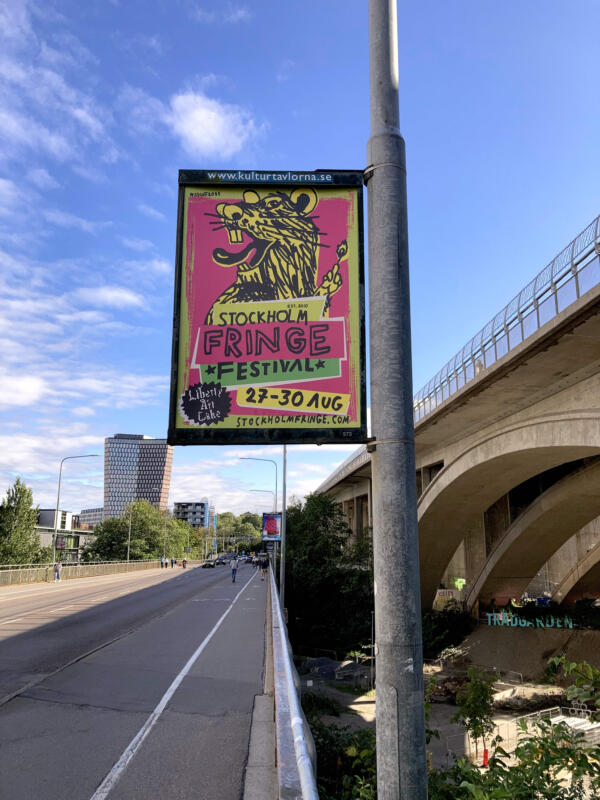 Affisch för Stockholm Fringe festival 2025. En råtta som tänder ett ljus. Kulörglatt och skrikigt. Liberty, Art & Cake