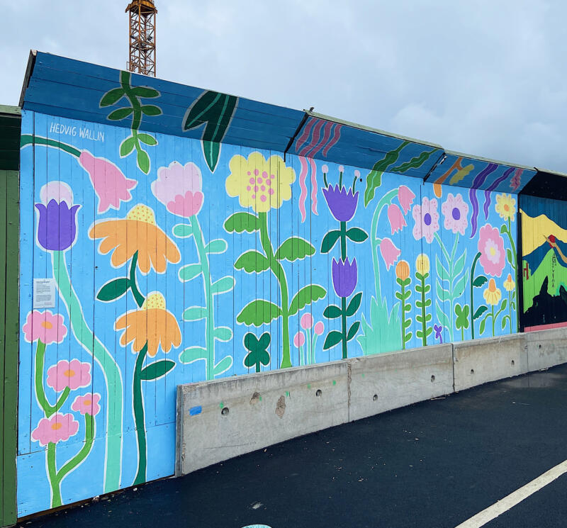 En väggmålning / muralmålning på ett byggplank i Göteborg. Målningen består av färgglada, fantasifulla blommor och grönska i lekfulla, organiska former.