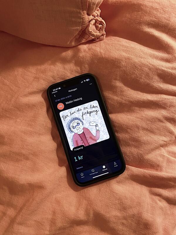 Vykort i swish-appen av en tant som håller ett kuvert. I illustrationen står också texten "Här har du en liten fickpeng"