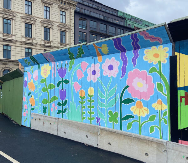En väggmålning / muralmålning på ett byggplank i Göteborg. Målningen består av färgglada, fantasifulla blommor i lekfulla, organiska former.