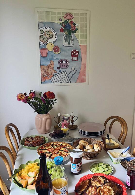 Tavla med frukosttema på väggen framför ett bord uppdukat med brunch.