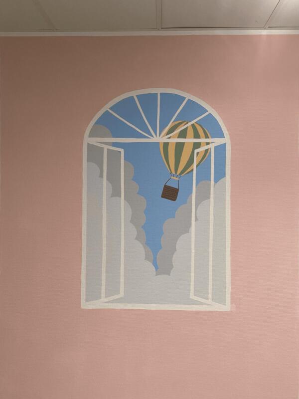Muralmålning i mjuka pastellfärger som föreställer en luftballong utanför ett fönster