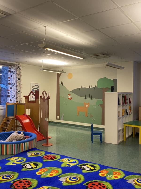 En förskola med en målad vägg som föreställer skog med söta djur
