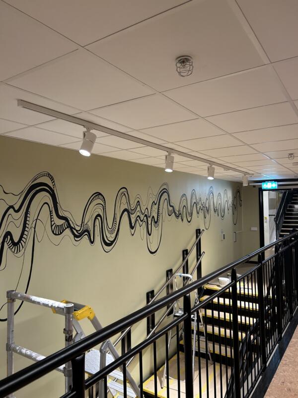 Väggmålning med svarta vågiga linjer som ska föreställa ljudvågor och DNA åt en musikproducent 