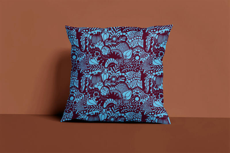 Produktbild. Kudde i blommigt och grafiskt mönster i färgerna ljusblått och vinrött. Mönstret heter 'Lush'.