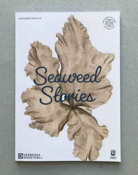 På bilden visas en utställningskatalog med en omslagsbild, envetenskaplig illustration i akvarell av algen purpurhinna.