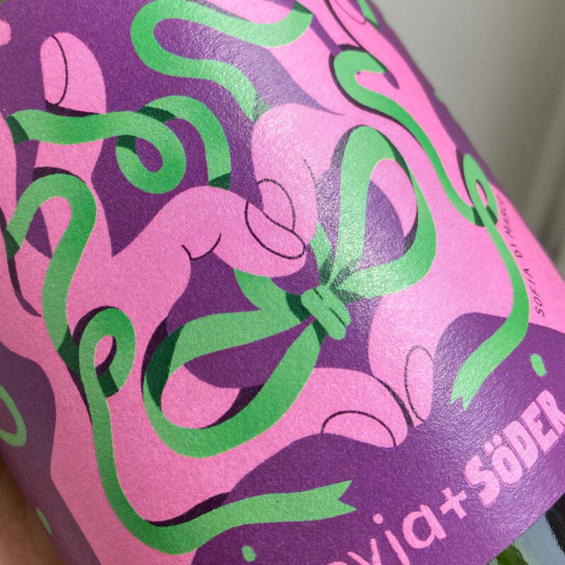 Närbild på etiketten med en grön rosett och två rosa händer som gör ett hjärta