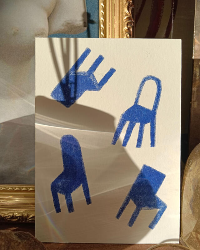 Vykort med fyra stolar i interiör med konst i bakgrunden 