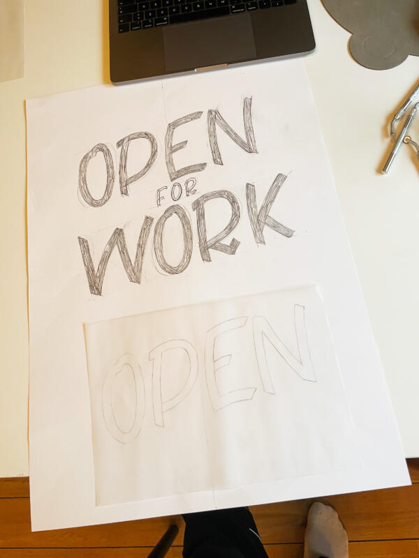 Vitt papper på ett bord med texten "Open for Work" I blyerts.
