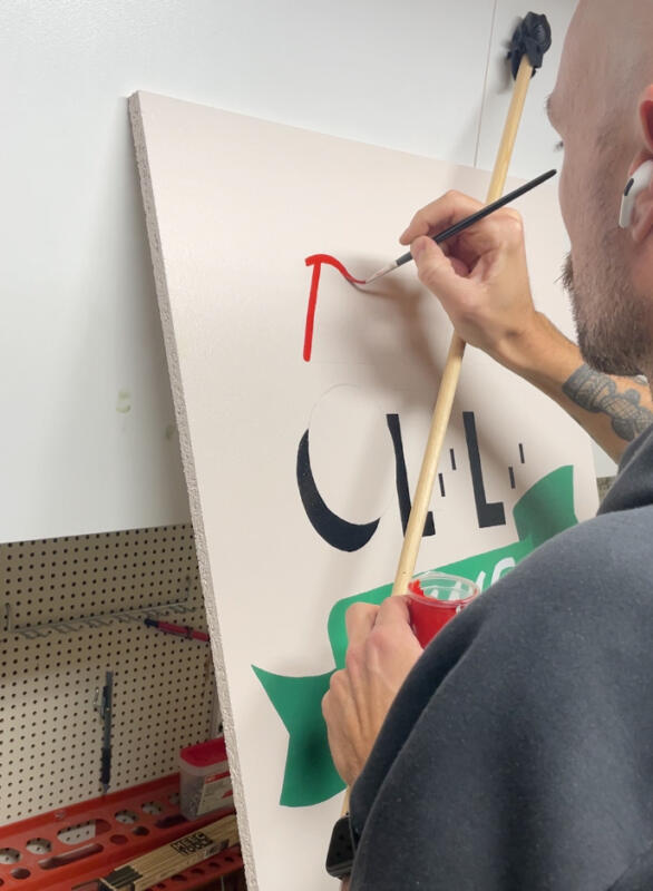 Process video of how a hand-painted sign with the message "Phones Off, Game On" was made. The preview shows a man holding a brush and a mahlstick, painting letters in red.