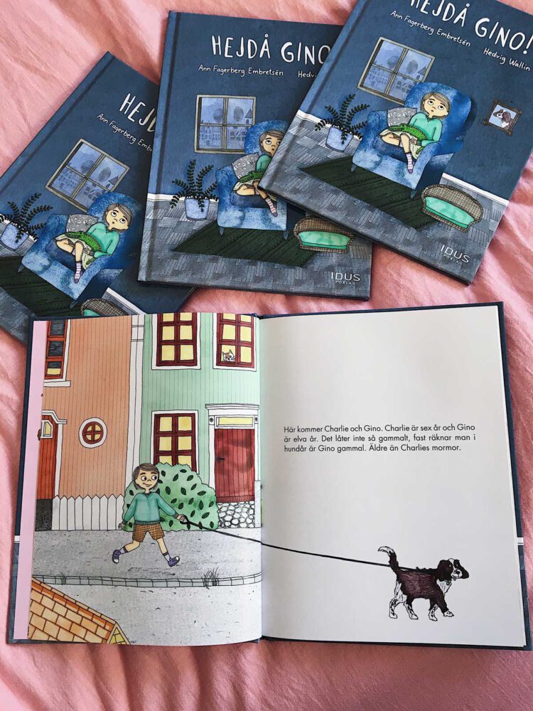 Barnboksillustration av ett barn som går framför färgglada hus med en hund i koppel