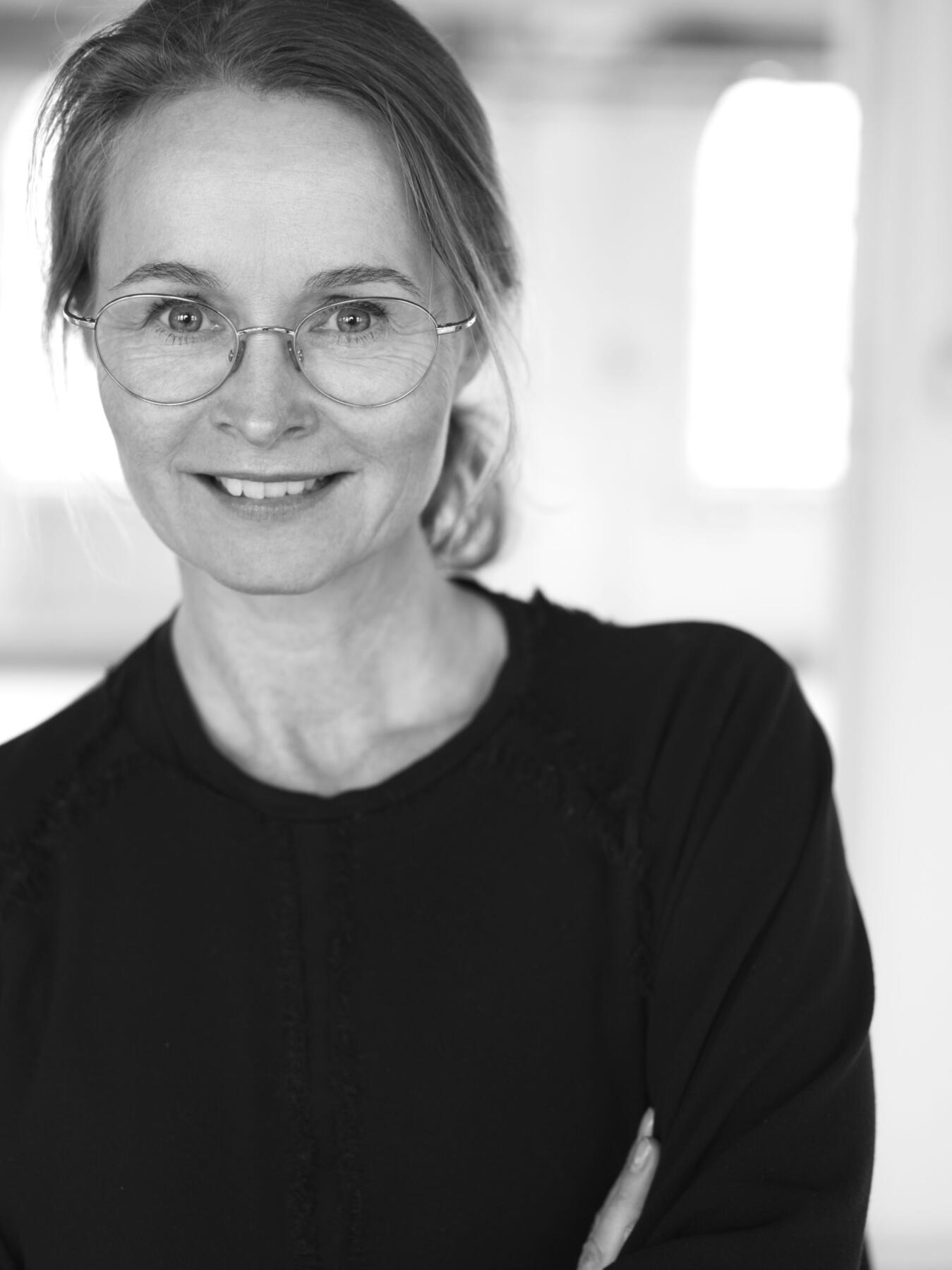 Bild på kvinna med ljust hår och glasögon, bilden är i gråskala.