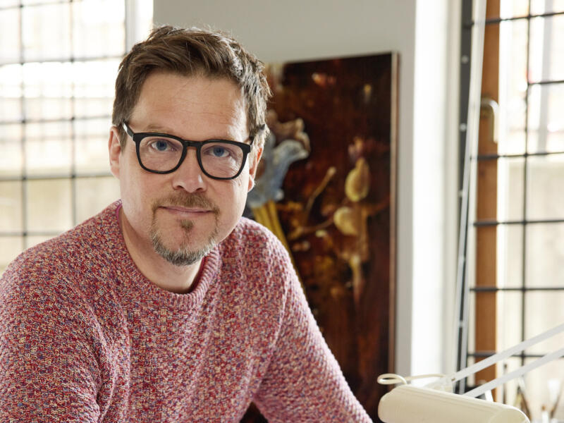 Illustratören, en man, står med pennan i hand mot ett ritbord