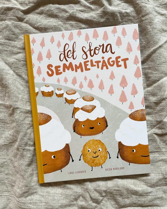 Omslagsbild av barnboken Det stora Semmeltåget. Illustrerade semlor står i led. 