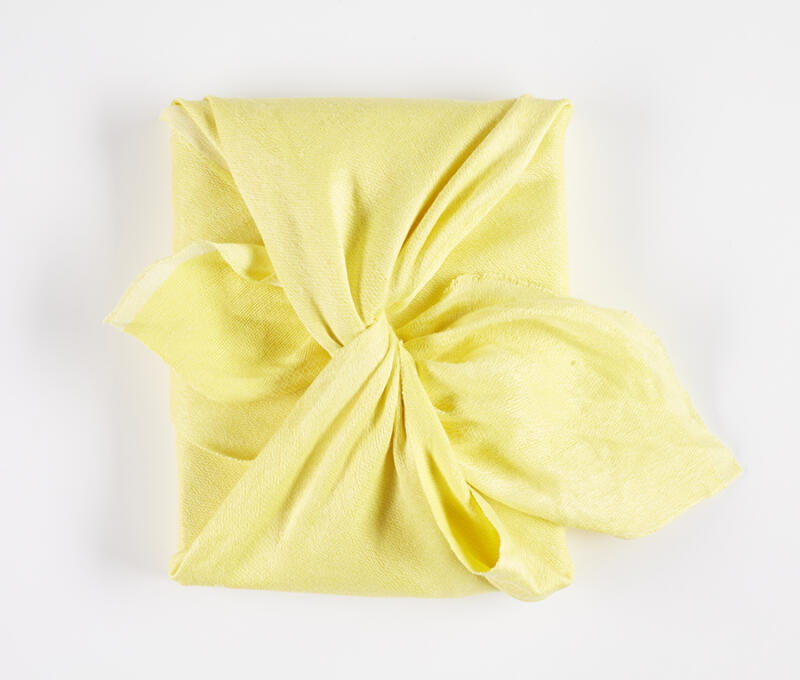 Bokomslag med handvävd knuten gul japansk furoshiki textil gjord av författaren. Furoshiki är en japansk textil och förpackningskonst. 