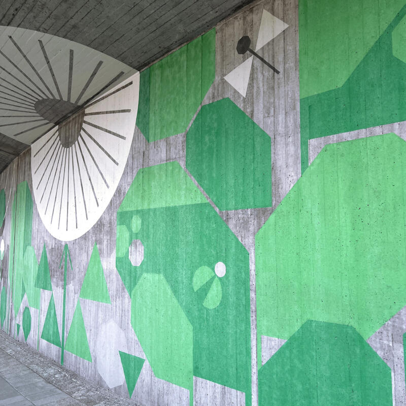 Muralmålning om växter och djurliv på grå betongvägg.