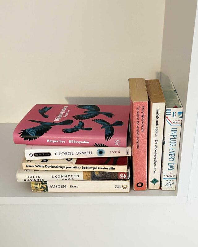 Bokhylla med flera böcker. En av böckerna är Dödssynden av Harper Lee. På omslaget syns blå fåglar mot en rosa bakgrund.
