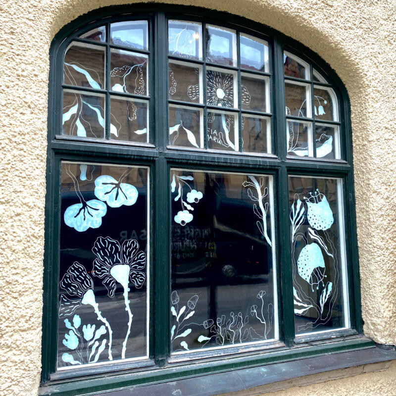 Foto på fönster med vita blommiga illustrationer. 