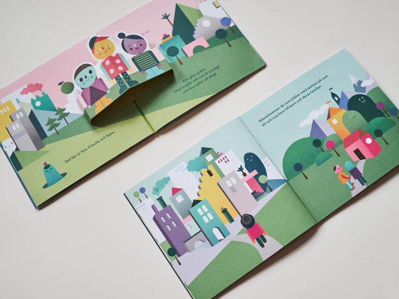 Uppslag med "pop-up" effekt från broschyren Kim Charlie och Sassa hälsar på hos socialtjänsten. Motiv: stad, människor, vuxna och barn, miljö, himmel, figur. boklayout, grafiska illustrationer, färgstarkt, lekfullt