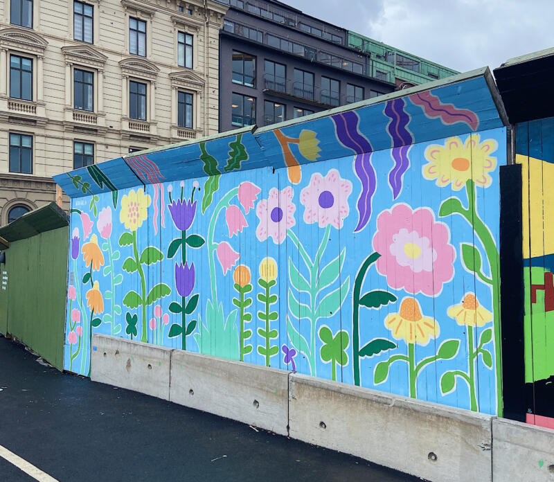 En väggmålning / muralmålning på ett byggplank i Göteborg. Målningen består av färgglada, fantasifulla blommor i lekfulla, organiska former.