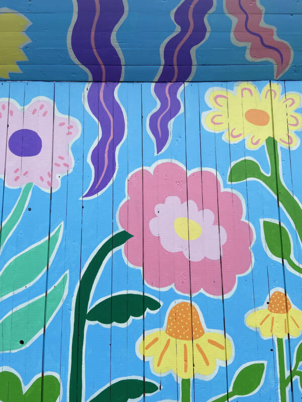Detaljer av en väggmålning / muralmålning på ett byggplank i Göteborg. Målningen består av färgglada, fantasifulla blommor.