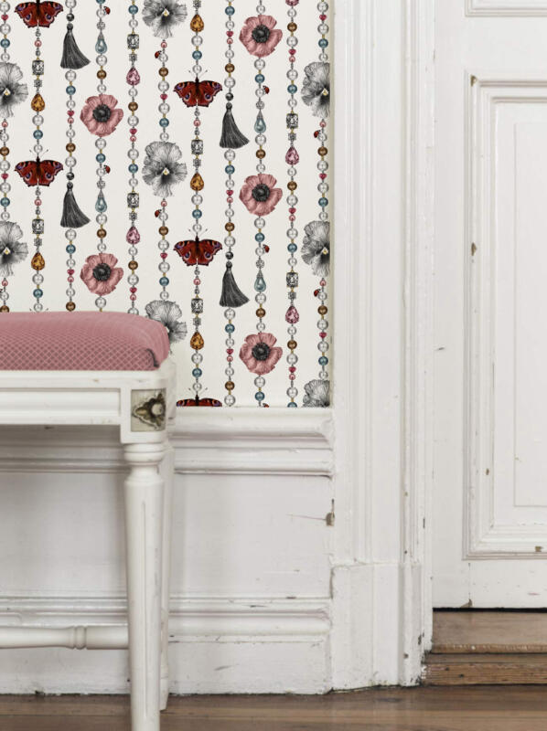 En interiör i shabby-chic stil med en 1700-tals pall och en tapet med ett överdådigt och skimrande mönster som gör väggen till ett smycke med pärlor, ädelstenar, blommor, fjärilar, nyckelpigor och tofsar i mönsterrapporten.