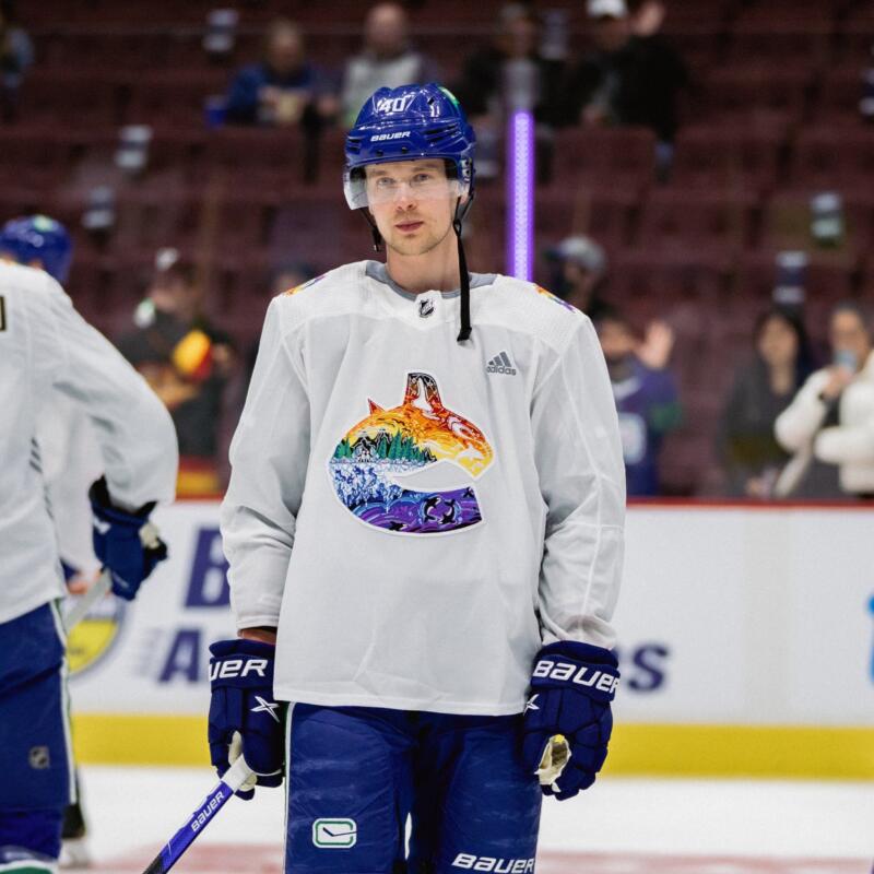 Elias Pettersson standing in the middle photographed in the Vancouver Pride Jersey from 2022. 