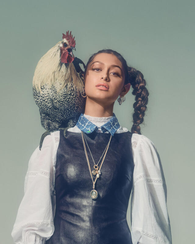 Girl in white shirt and black leather dress with a rooster on her shoulder and a blue faux collar